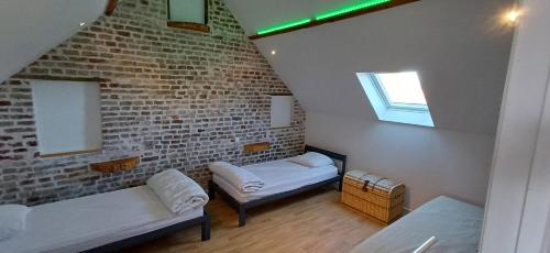 Cette chambre comprend 2 lits et un mur en briques. dans l'établissement La Paillote relais du Chatô n3, à Quend