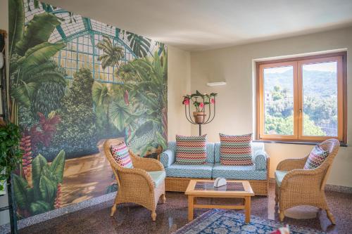 a living room with a couch and chairs and a mural at Hotel Villa Edera & La Torretta in Moneglia