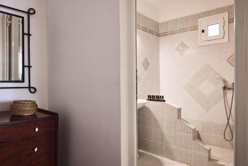 a bathroom with a walk in shower next to a staircase at Tramontana Suites in Áyios Stéfanos
