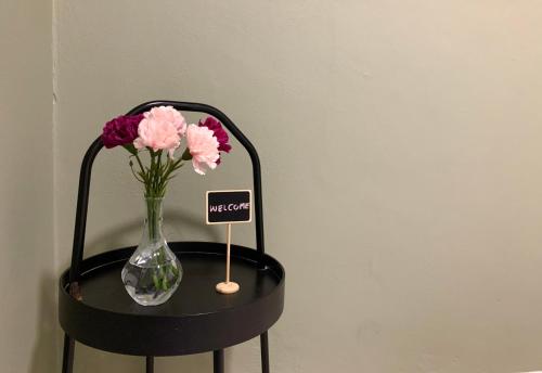 a vase of flowers on a table with a sign on it at Ellie House Phuket Old Town in Ban Rangeng