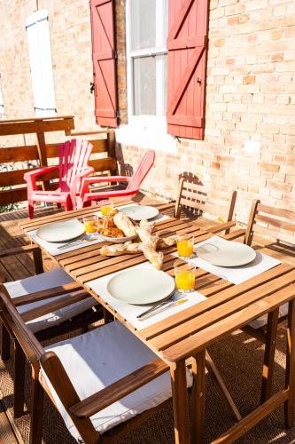 a wooden table with chairs and plates on it at Grand appartement Familiale - Camargue in Salin-de-Giraud