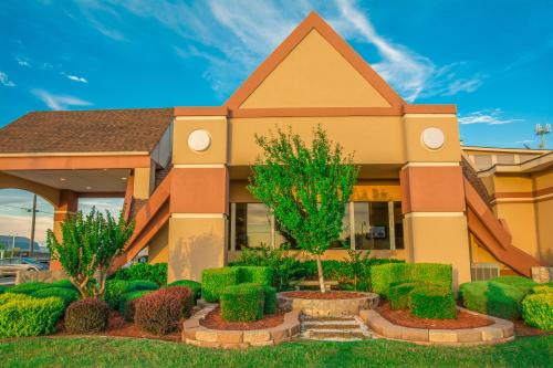 a building with trees and bushes in front of it at Howard Johnson by Wyndham Oklahoma City OKC Airport, Fairgrounds, I40 in Oklahoma City