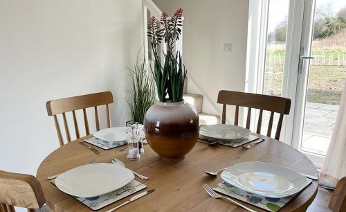 a wooden table with plates and a vase with flowers on it at Linwood in Lincoln