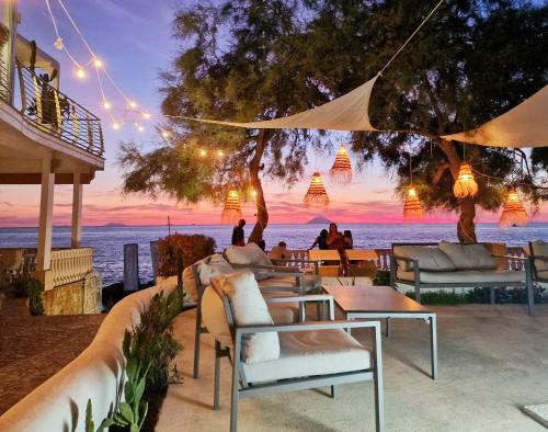 un ristorante con vista sulla spiaggia al tramonto di Hotel resort Rocca di Vadaro a Capo Vaticano