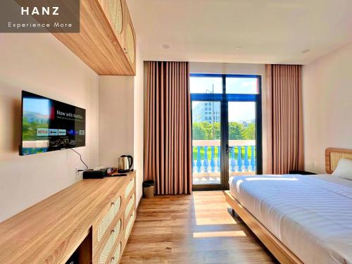 a bedroom with a bed and a television and a balcony at HANZ Sofia Hotel Grand World in Phu Quoc