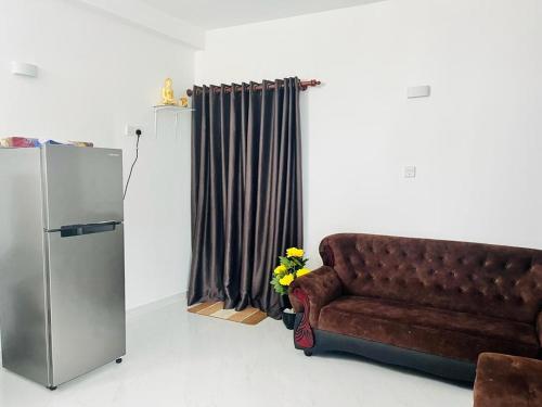 eine braune Couch im Wohnzimmer neben einem Kühlschrank in der Unterkunft Villa Yoshan in Ambalangoda