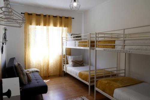 a room with two bunk beds and a couch at *Private Outdoor Area* 300m-Beach, Swing/No Stairs in São Martinho do Porto