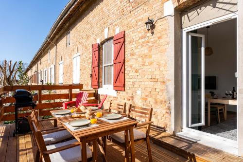 a patio with a wooden table and chairs on a balcony at Grand appartement Familiale - Camargue in Salin-de-Giraud