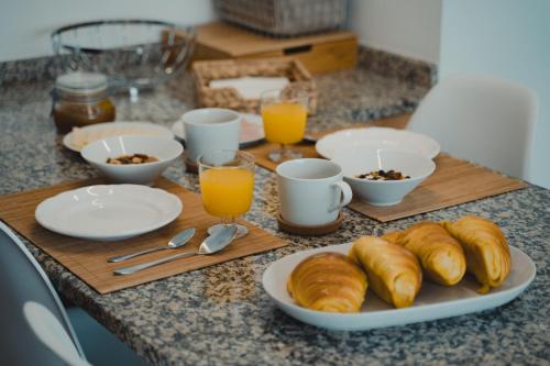 a breakfast table with croissants and glasses of orange juice at marAnorte - T2 com terraço a 600m da praia in Moledo