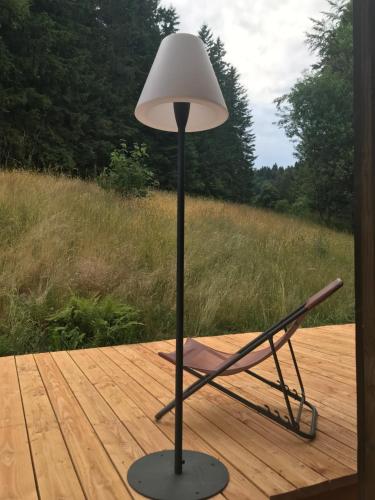 a lamp and a chair on a wooden deck at La maison de Cécile in Ventron