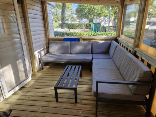 a screened in porch with a couch and a bench at mobil home 441 in Pont-Aven