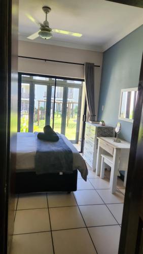 a bedroom with a bed and a desk and a window at Topanga 17 in Uvongo Beach