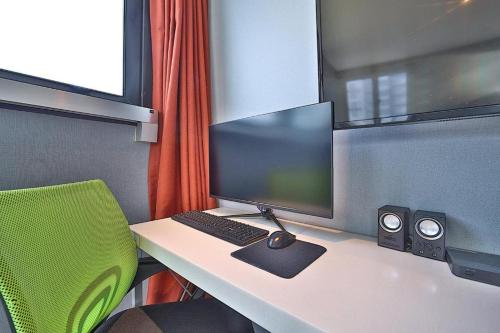 a desk with a computer monitor and a green chair at Hermes Hotel in Busan