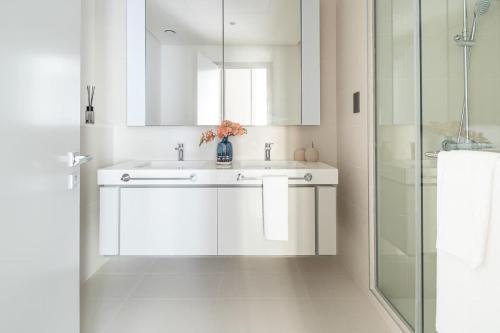 uma casa de banho branca com um lavatório e um chuveiro em Frank Porter - Sunrise Bay at EMAAR Beachfront em Dubai
