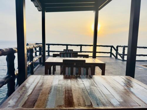 een houten tafel op een pier met uitzicht op de oceaan bij Ocean Front Apartments in Ko Tao