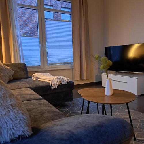 a living room with a couch and a tv and a table at Seeliebe, 300 Meter zum Wasser, mit Terrasse und Garten in Lembruch
