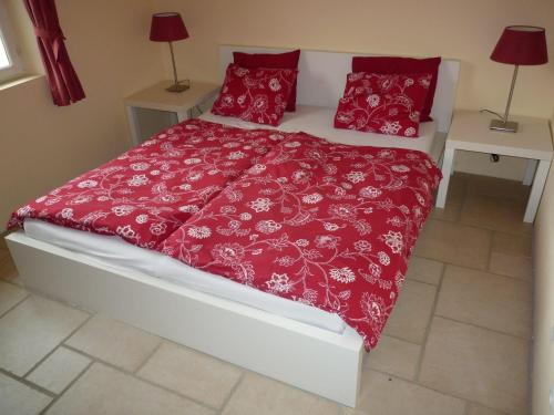 uma cama com um edredão vermelho e almofadas vermelhas em Villa Fleury Appartement em Montbrun-les-Bains