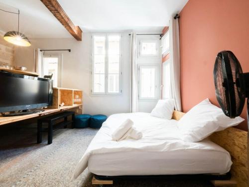 um quarto com uma cama e uma secretária com uma televisão em Le hollandais - Cœur de ville em Montpellier