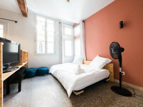 une chambre avec un lit, un bureau et une télévision dans l'établissement Le hollandais - Cœur de ville, à Montpellier