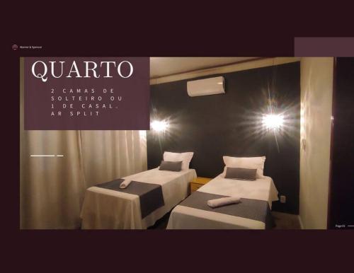 a room with two beds and a sign that says quarto at Eletric Car Flat in Teófilo Otoni