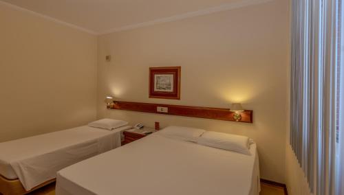 a room with two beds in a hotel room at Lizon Curitiba Hotel in Curitiba