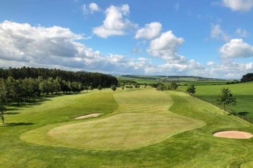 a view of a green golf course with trees at Birch Tree Lodge 96 Main park in Jedburgh