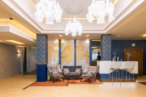 a lobby with chairs and a table and chandeliers at Elements Kirov Hotel in Kirov