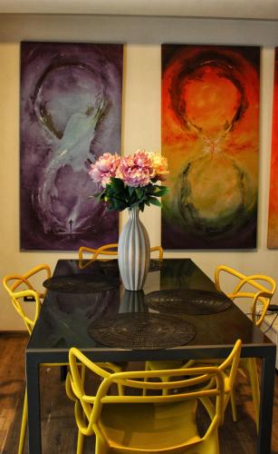 a dining room table with a vase of flowers and paintings at Amazing Park Residences 5 in Bucharest