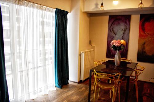 a dining room with a table with a vase of flowers on it at Amazing Park Residences 5 in Bucharest