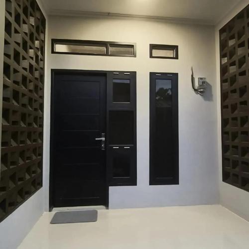 twee zwarte deuren op een witte muur met wijnrekken bij Zio Zildan Homestay in Sibengkok