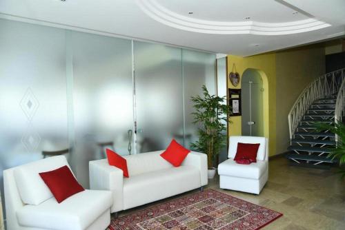 ミザーノ・アドリアーティコにあるHotel Villa Rosaのリビングルーム(白い椅子2脚、赤い枕付)