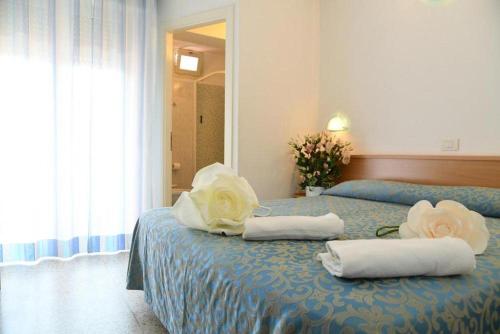 ミザーノ・アドリアーティコにあるHotel Villa Rosaのベッドルーム1室(タオル、花付)