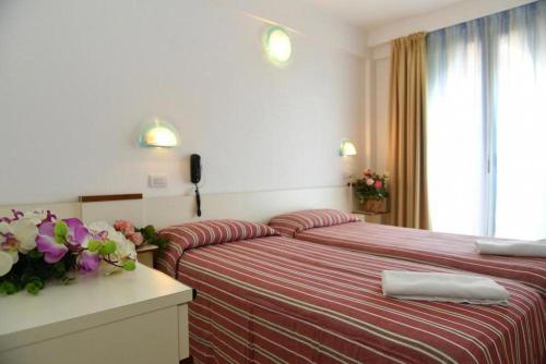 ミザーノ・アドリアーティコにあるHotel Villa Rosaのベッド2台 ホテルルーム 花のテーブル付
