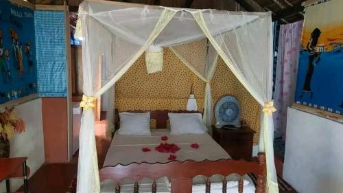 Un dormitorio con una cama con dosel y flores. en Piscine bimoko, en Nosy Be