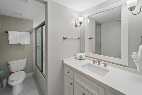 uma casa de banho com um lavatório, um WC e um espelho. em Newly Renovated Condo with Private Balcony! em Panama City Beach