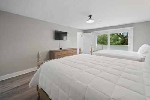 a white bedroom with a large bed and a window at Newly Renovated Condo with Private Balcony! in Panama City Beach