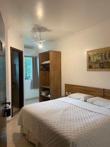 a bedroom with a white bed and a closet at Hotel Casa Branca in Monte Belo