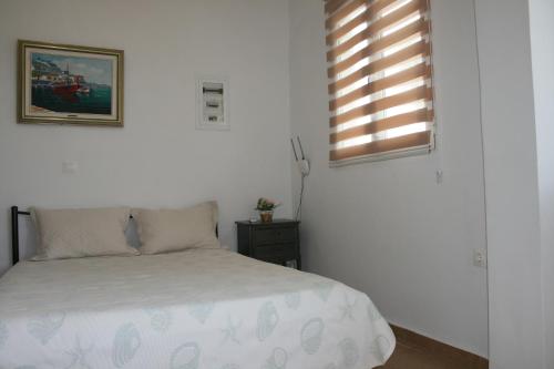 biała sypialnia z łóżkiem i oknem w obiekcie Theatraki w mieście Selínia