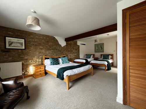 a bedroom with two beds and a brick wall at Kingfisher in Lyddington