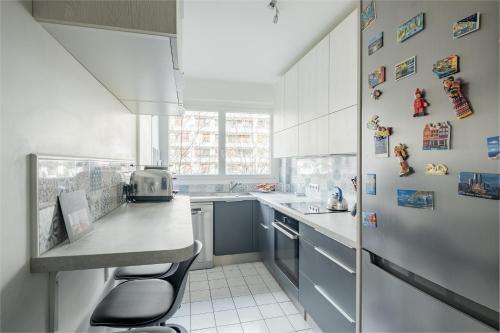 une cuisine avec des armoires blanches et un comptoir avec des tabourets dans l'établissement Veeve - Auteuil Adagio, à Paris