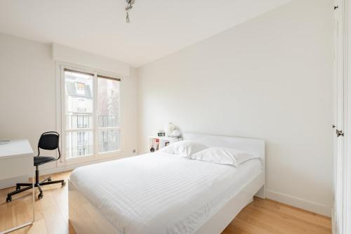 une chambre blanche avec un lit, un bureau et une fenêtre dans l'établissement Veeve - Auteuil Adagio, à Paris
