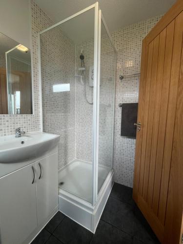 uma casa de banho branca com um chuveiro e um lavatório. em 246, Belle Aire, Hemsby - Beautifully presented two bed chalet, sleeps 5, pet friendly, close to beach! em Great Yarmouth