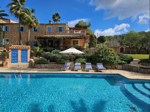 a swimming pool with two chairs and an umbrella at C'an Talaieta Luxurious Farmhouse in S'Horta