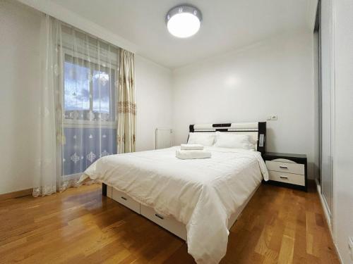 une chambre blanche avec un grand lit et une fenêtre dans l'établissement Fillettes-Stade de France-Parking, à Aubervilliers