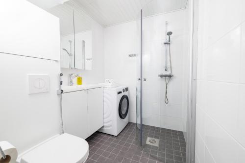 a white bathroom with a washing machine and a shower at ULEABO Bright Top Floor Studio in Oulu