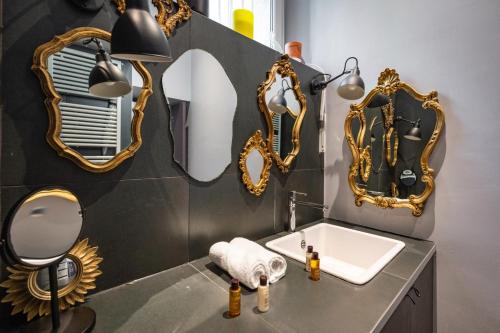 une salle de bain avec un lavabo et des miroirs au mur dans l'établissement Veeve - Haut Marais Glam, à Paris