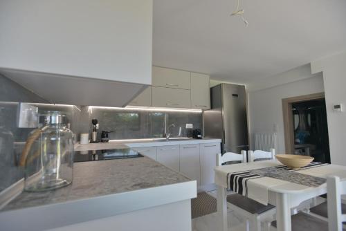 a kitchen with white cabinets and a table and chairs at Theros-Cottage in Siviri