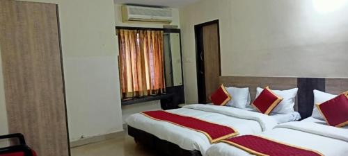a bedroom with two beds with red and white pillows at Chennai Guest House in Chennai