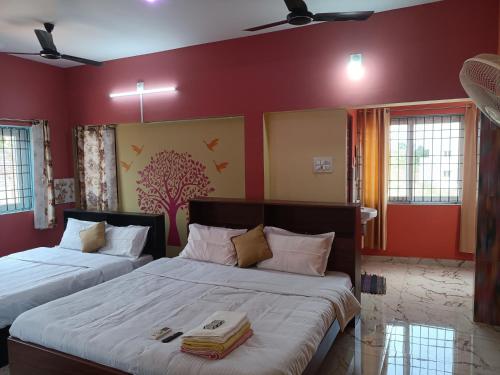 two beds in a room with red walls and windows at Guru Residency Pondicherry in Puducherry