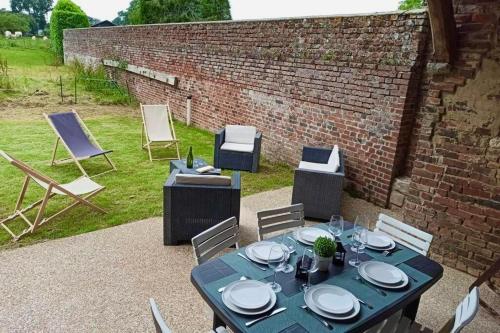 une table et des chaises bleues ainsi qu'un mur en briques dans l'établissement Gite de Beaufournier, à Avremesnil